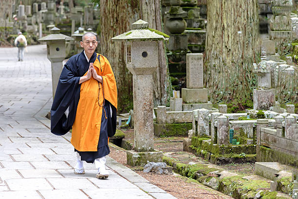Shingon Monk in Okunoin Cemetery at Kōya-san, Japan Koyasan, Japan - April 30, 2014: View of a Shingon Monk walking in Okunoin cemetery.  Koyasan is primarily known as the world headquarters of the Koyasan Shingon sect of Japanese Buddhism. shingon buddhism stock pictures, royalty-free photos & images