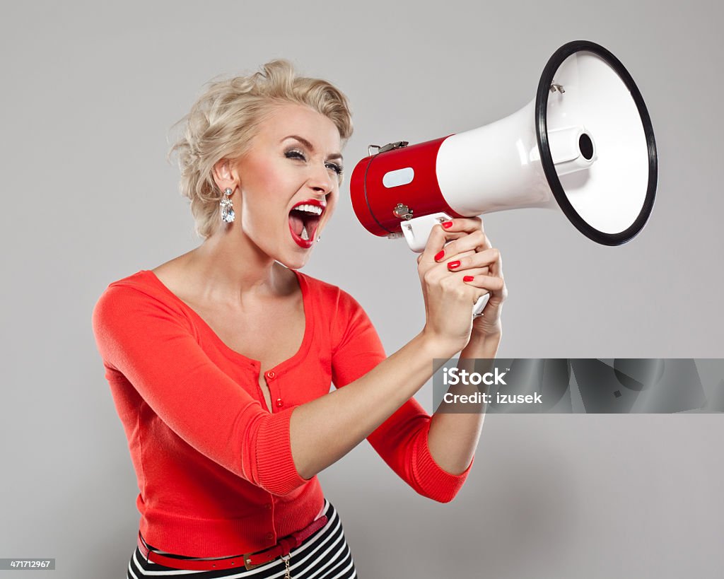Woman with megaphone Portrait of  elegant woman screaming into a megaphone. Studio shot on a grey background. Women Stock Photo