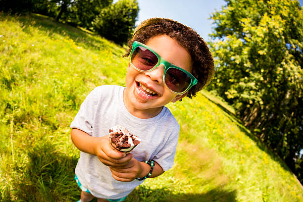 Handsome boy sitting on the beach wearing a t-shirt and eating ice cream on a stick