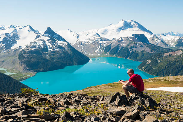 istock Man in red on a rock using cell phone over the mountains 471715569