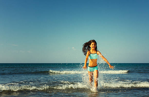 istock Young girl having fun running through the splashing waves 471715938