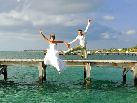 Newlyweds jumping of a dock shortly after saying their vows in the Caribbean
