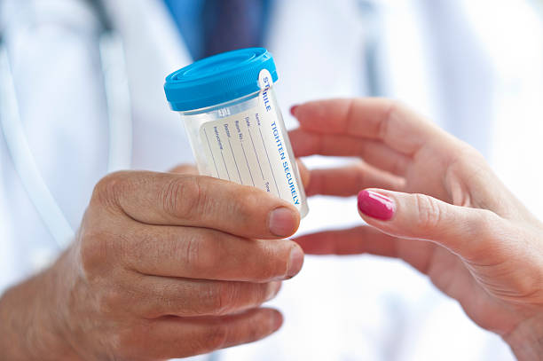 Doctor handing container with urine sample to a woman stock photo