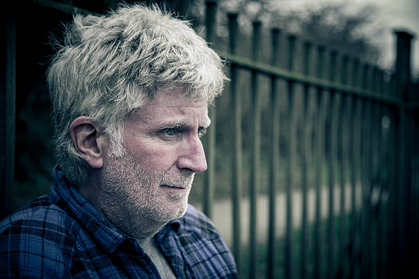 Poor homeless senior man holding coins outdoors. Black and white effect