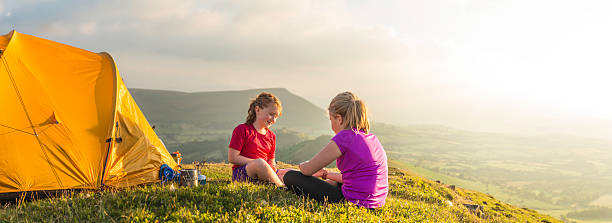 istock Children camping on green summer mountain overlooking sunlit valley panorama 471729049