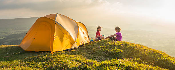 istock Kids camping beside colourful tent on summer sunset mountain top 471729057