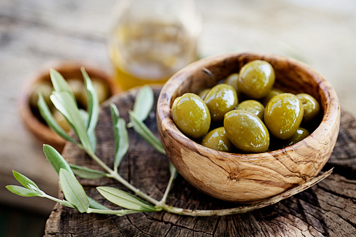 Fresh olives and olive oil  on rustic wooden background. Olives in olive wood.