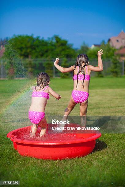 Two Little Sisters Frolicing And Splashing In Yard Stock Photo - Download Image Now - Activity, Child, Cute