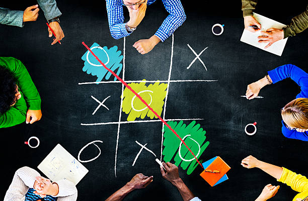Two female coworkers enjoying a friendly game of tic-tac-toe during a break, laughing and connecting in a bright, modern office space filled with creativity and collaboration