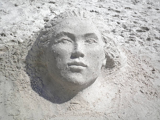 Beautiful woman face from wet sand on summer beach