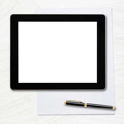 Tablet pc with blank screen and pen over table.