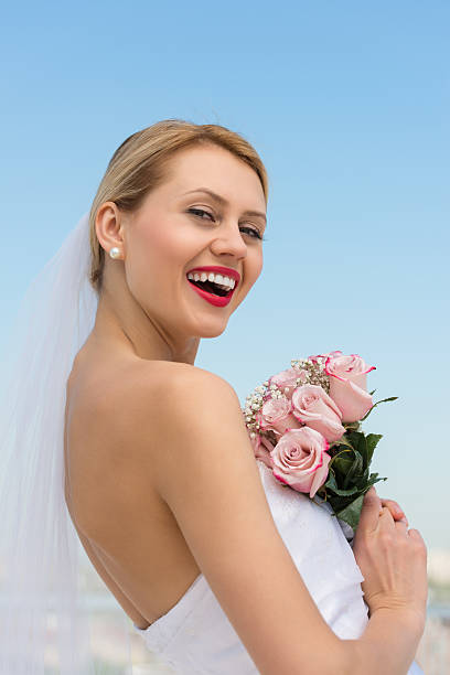 istock Cheerful Bride With Flower Bouquet Against Clear Blue Sky 471735305