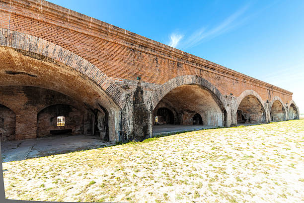 A view through a partial casemate wall of the fort at the ferry and dock with the salt water moat between the beach and fort walls. Fort Jefferson in the Dry Tortugas is a national park in the Florida Keys and was built to protect an important merchant shipping route for the Gulf coast of the United States. The never completely finished fort was built starting in 1845, Though never completed was the fort was used during the Civil War. The tropical pristine waters surrounding the Dry Tortugas islands protect marine life and provide recreational opportunities. The archipelago's coral reefs are the least disturbed of the Florida Keys.