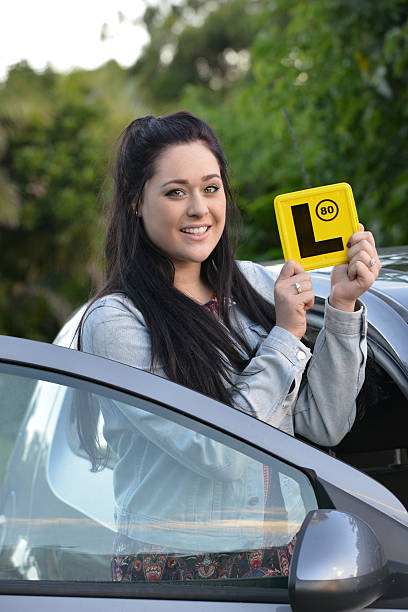 Young Australian female teenager learner driver holding an L plate