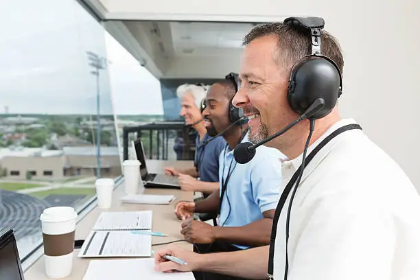 Sports commentators covering game from stadium press box