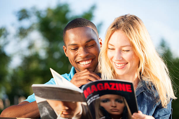 istock Diverse couple having fun reading magazine outdoors 471741987