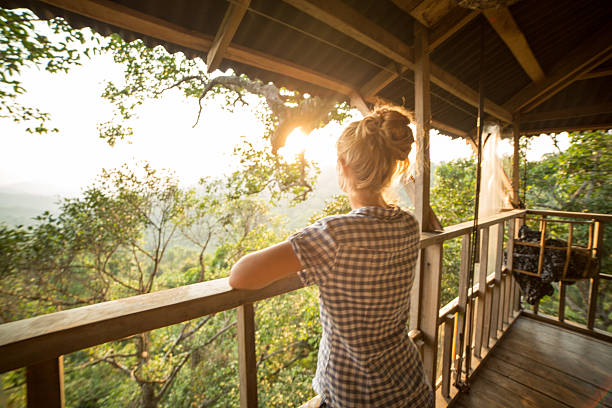 Woman on tree house looking at sunset Young woman on a canopy tour adventure in the rain forest in northern Laos looking at the beautiful natural landscape in a sunny summer day. She is on a tree house up in the jungle. canopy tour photos stock pictures, royalty-free photos & images