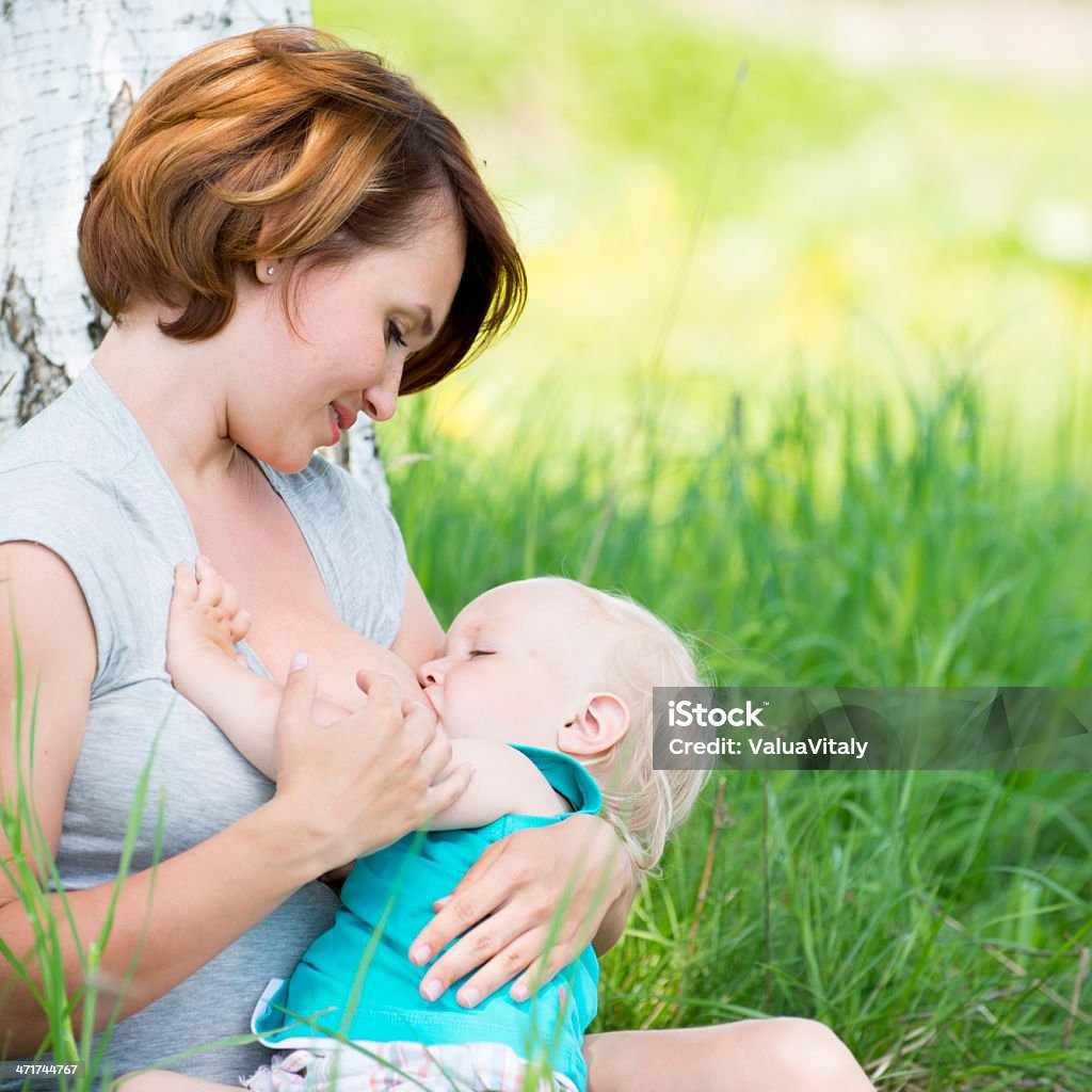 Young mother breastfeeding a baby in nature Adult Stock Photo