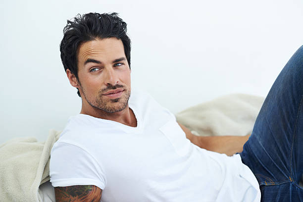 He's go that casual charm Shot of ruggedly handsome man wearing a white t-shirt and lying on a bedhttp://195.154.178.81/DATA/shoots/ic_781840.jpg sex symbol stock pictures, royalty-free photos & images