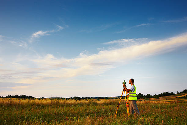 Land surveyor Land surveyor working with total-station. A lot of copy space. surveyor photos stock pictures, royalty-free photos & images