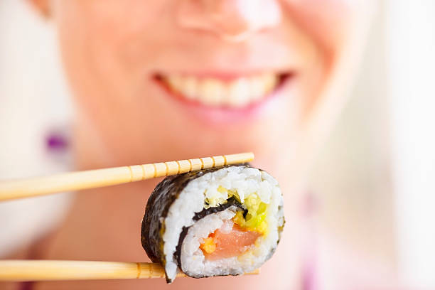 istock young woman eating sushi 471746557