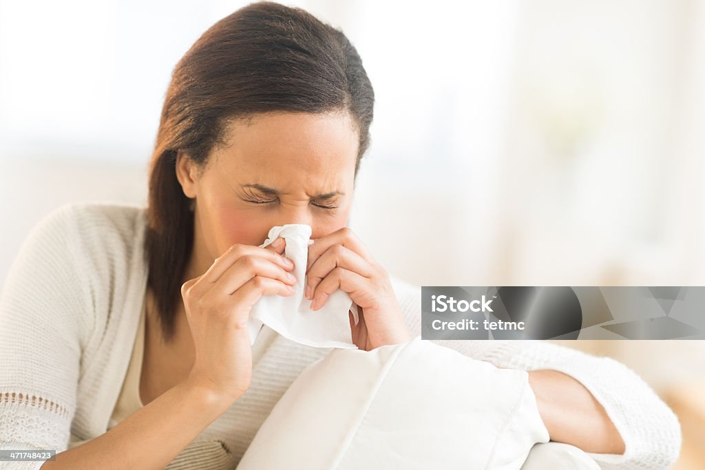 Woman Blowing Nose With Tissue At Home Young woman blowing nose with tissue at home 20-29 Years Stock Photo