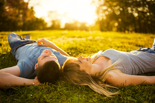 Teenage couple lying in the park at sunset.   