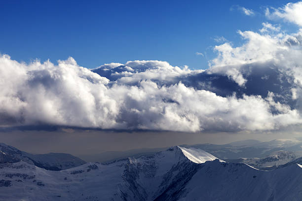 Winter mountains in evening and sunlight clouds. Caucasus Mountains, Georgia, view from ski resort Gudauri.