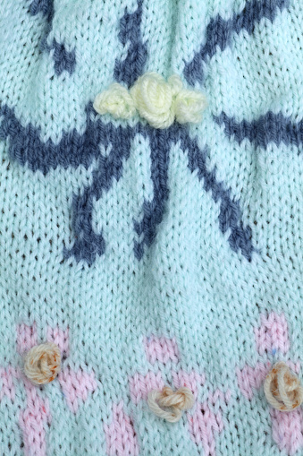 Spider big flower with small ones below on a blue stocking stitch knitted fabric