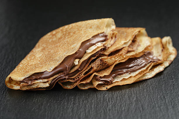 thin crepes or blinis with chocolate cream on slate board thin crepes or blinis with chocolate cream on dark slate board blini photos stock pictures, royalty-free photos & images