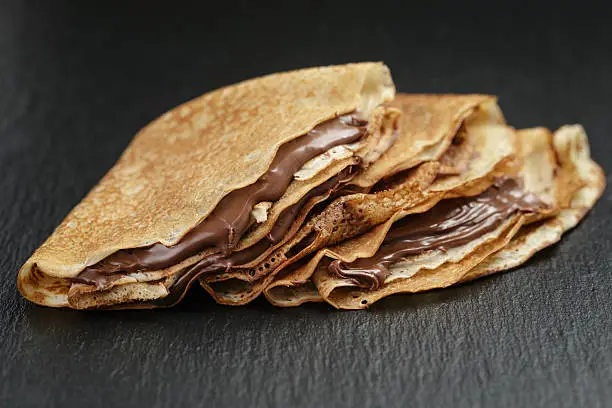 thin crepes or blinis with chocolate cream on dark slate board