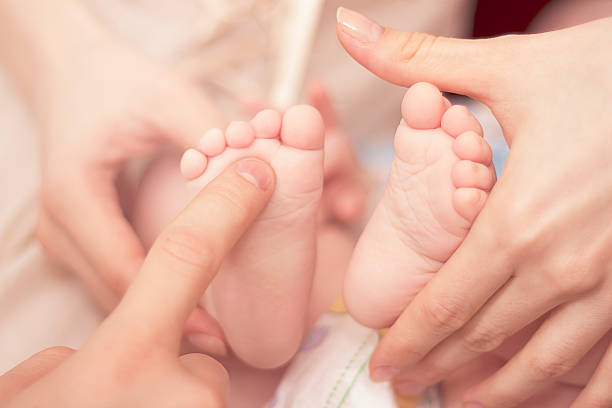 close up of baby's heels and parent's hands stock photo