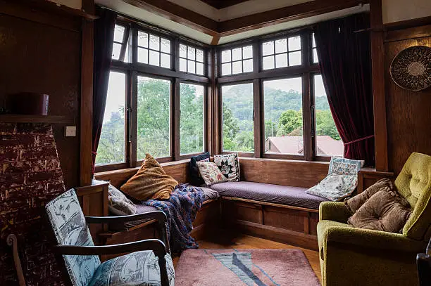 Living room in 1920s bungalow with vintage furniture and view to surrounding woodland