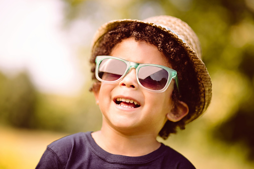 Happy kid smiling at camera with hat and sunglasses...vintage color correction