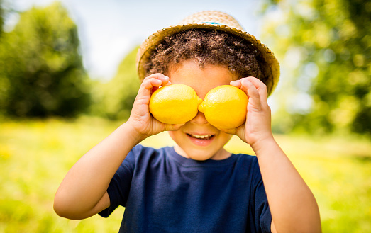 Cheerful kid holding lemons as eyes looking at camera as a good concept  for healthy eating, lifestyle and vitamin C