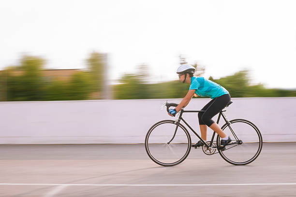 jovem atleta feminina num movimento de corrida turva bicicleta. imagem - racing bicycle cyclist sports race panning imagens e fotografias de stock