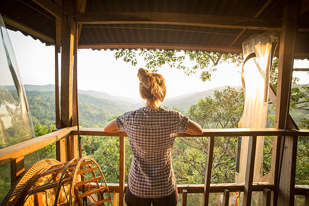 Woman on tree house watching sunset Young woman on a canopy tour adventure in the rain forest in northern Laos looking at the beautiful natural landscape in a sunny summer day. She is on a tree house up in the jungle. canopy tour photos stock pictures, royalty-free photos & images