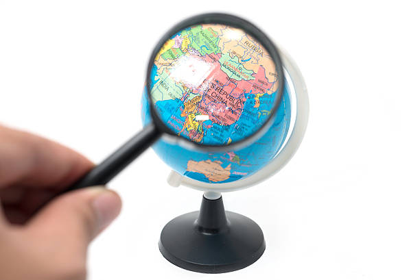 istock hand holding magnifying glass over earth globe 471757382