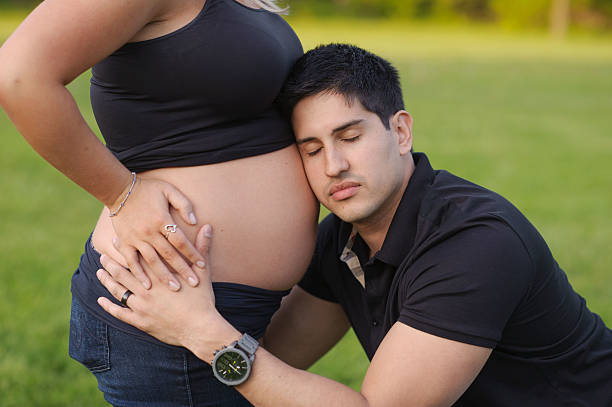 istock Serious Husband Hugging Wife's Pregnant and Bare Belly 471759693