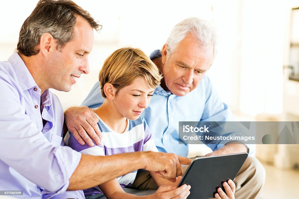 Nieto con padre y abuelo usando tableta Digital en su hogar - Foto de stock de 10-11 años libre de derechos