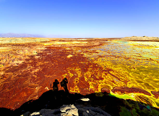 Wow Dallol Two photographers at Volcanic remains after 1926 eruption as Hot Springs and geothermal / volcanic activity on Dallol Mountain. The characteristic white, yellow and red colours are the result of sulphur and potassium salts coloured by various ions. It is located in the Danakil Depression with the highest average temperatures on the planet and is considered the most remote and beautiful place on Earth, North East Ethiopia near Eritrea in Africa. danakil depression stock pictures, royalty-free photos & images