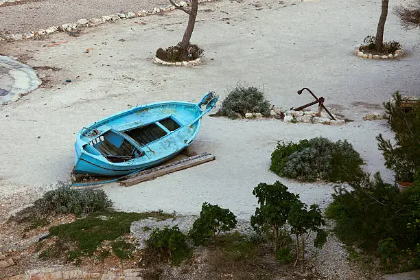 Old blue wooden boat marooned on beach.