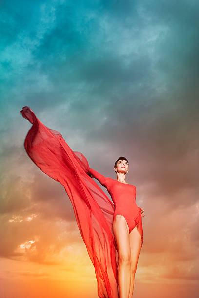 istock Beautiful woman with red chiffon in front of cloud background 471765171