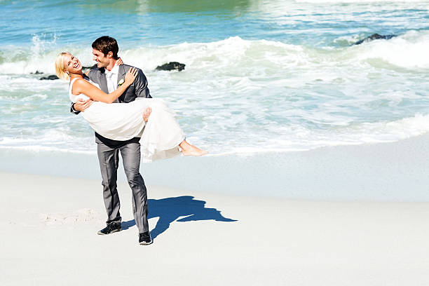 istock Cheerful Groom Carrying Bride While Walking On Beach 471766095