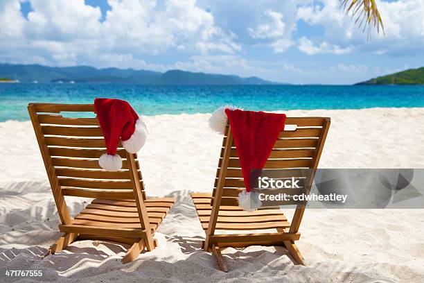 Foto de Cadeiras Com Chapéus De Natal Sob As Palmeiras Em Uma Praia e mais fotos de stock de Cadeira de Praia