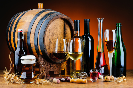 still life with different alcoholic drinks and wooden barrel