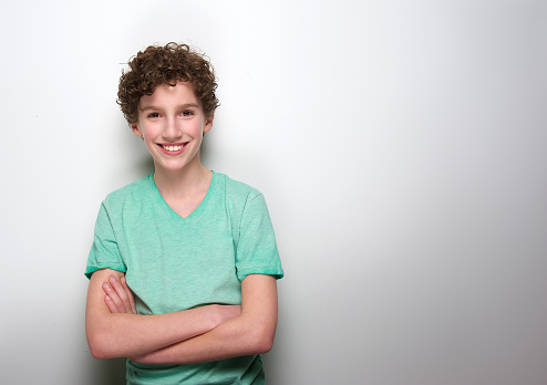 Portrait of a smiling boy with curly hair posing against white background