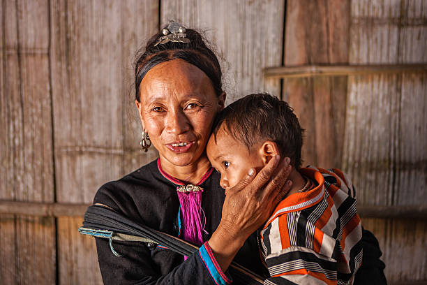 женщина с hill tribe носить ее ребенка - laos hut southeast asia shack стоковые фото и изображения