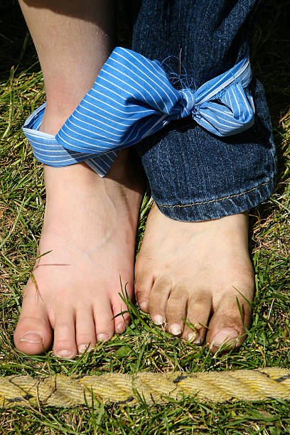 two feet tied together for three-legged race two feet tied together with blue fabric ready at start line for a three-legged race three legged race stock pictures, royalty-free photos & images