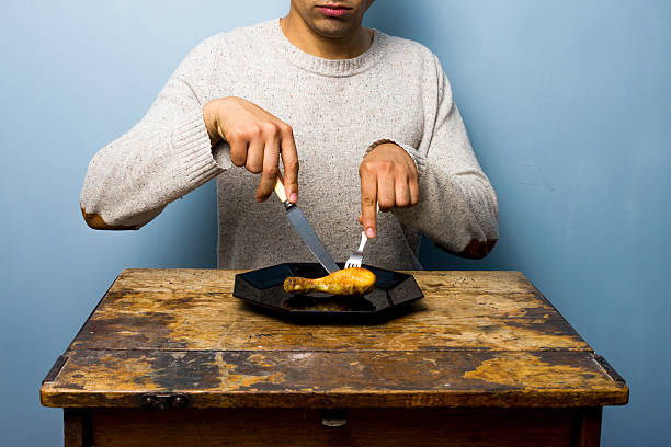 istock Young man having a chicken drumstick to eat 471769821